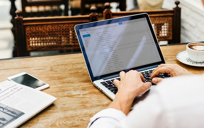An employee drafts an email on his laptop.