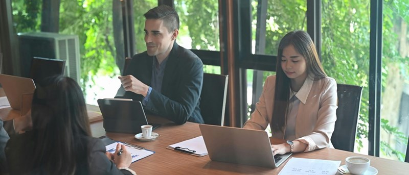 Worker shares thoughts with fellow employees during a meeting.