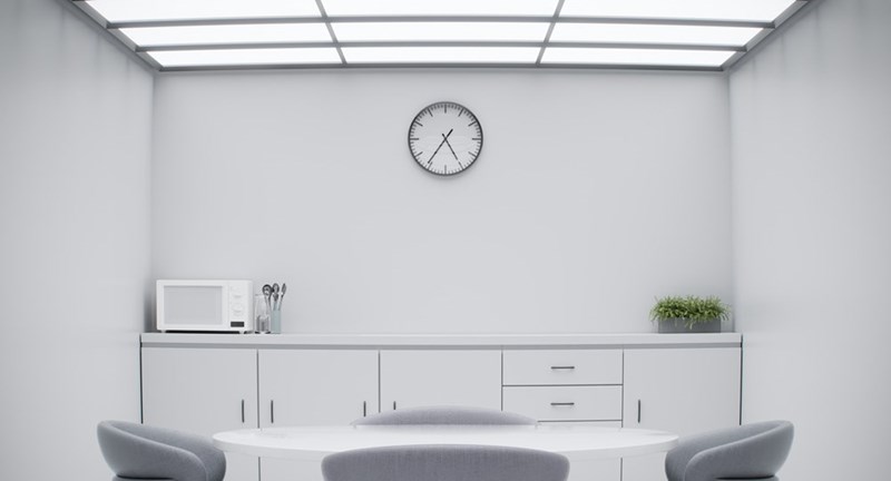 A white microwave in a white kitchen in an office building for employees