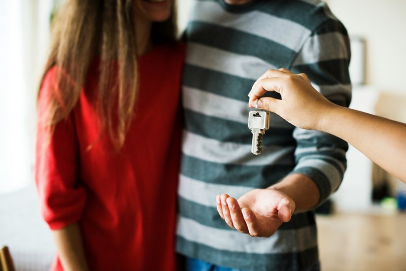 Landlord handing townhouse keys to a new renter couple.