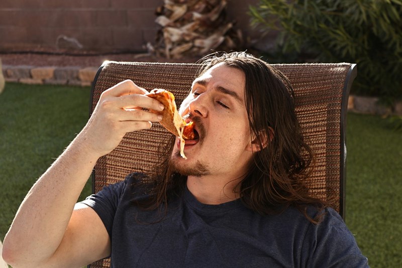 A man enjoys a slice of pizza