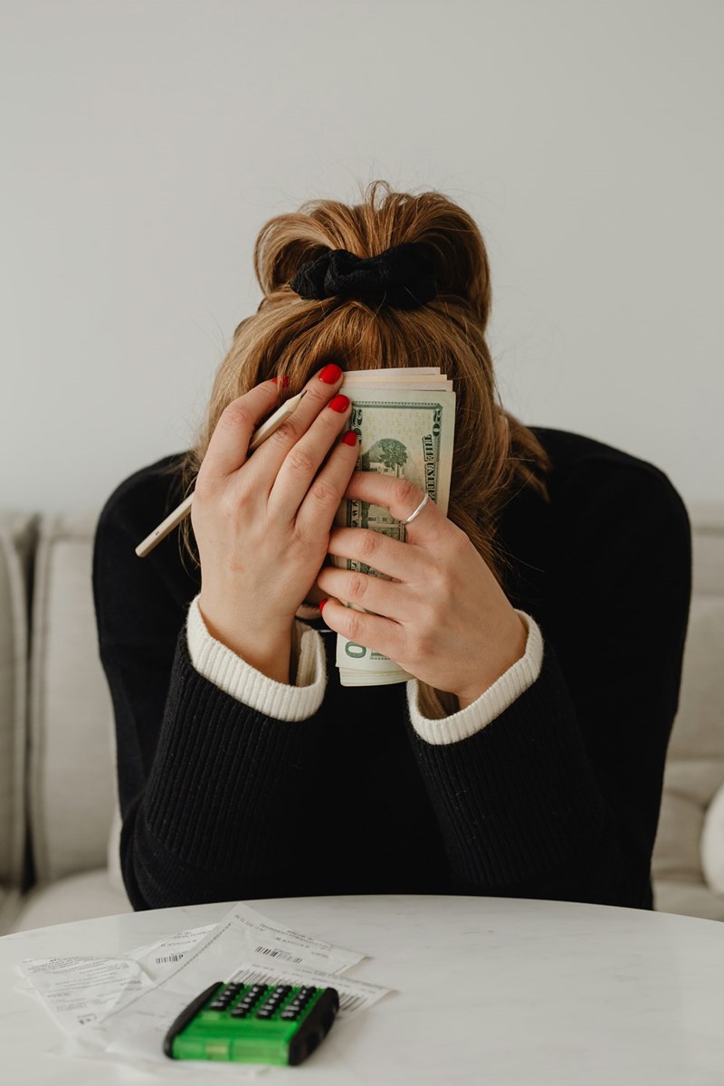 A woman sitting at a table holding a stack of money