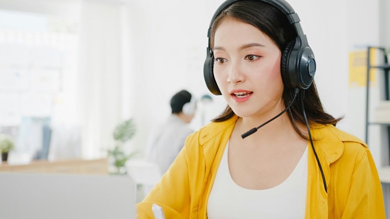 Customer service representative with headset speaking during call at modern call center workspace