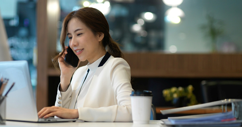 A front desk employee speaking on the phone as she looks at a laptop