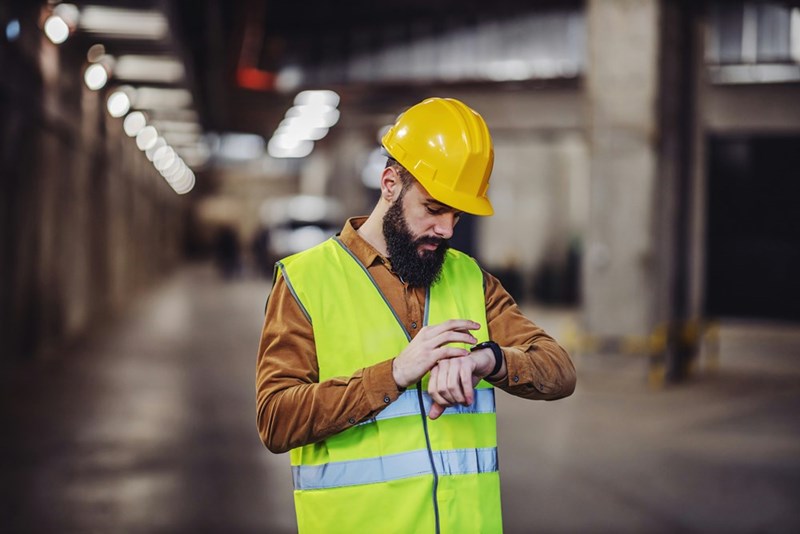 Employee checking time, waiting to finish his shift at the workplace.