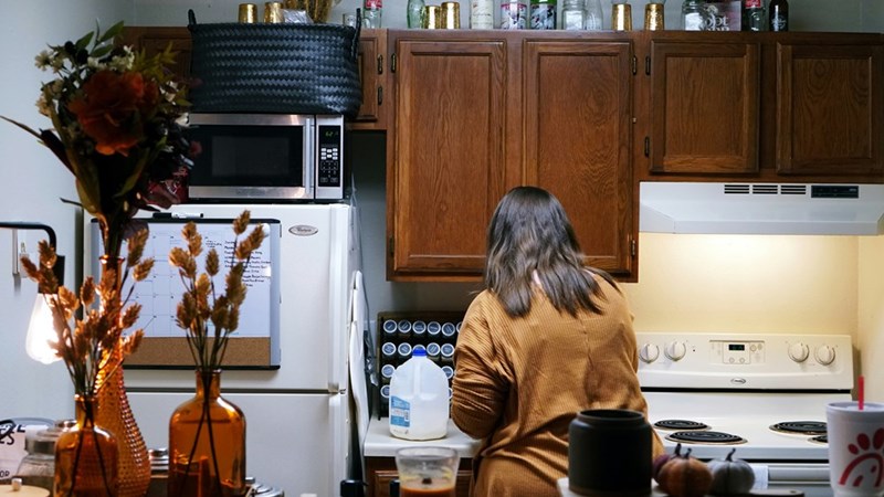 A woman standing in a kitchen next to a stove top oven