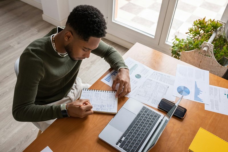 A man sits at a table working on a laptop