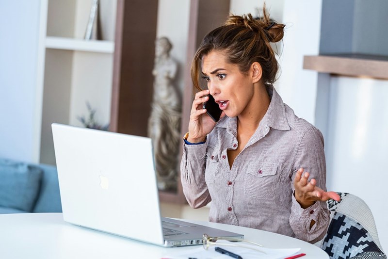 A woman looks at her phone, upset