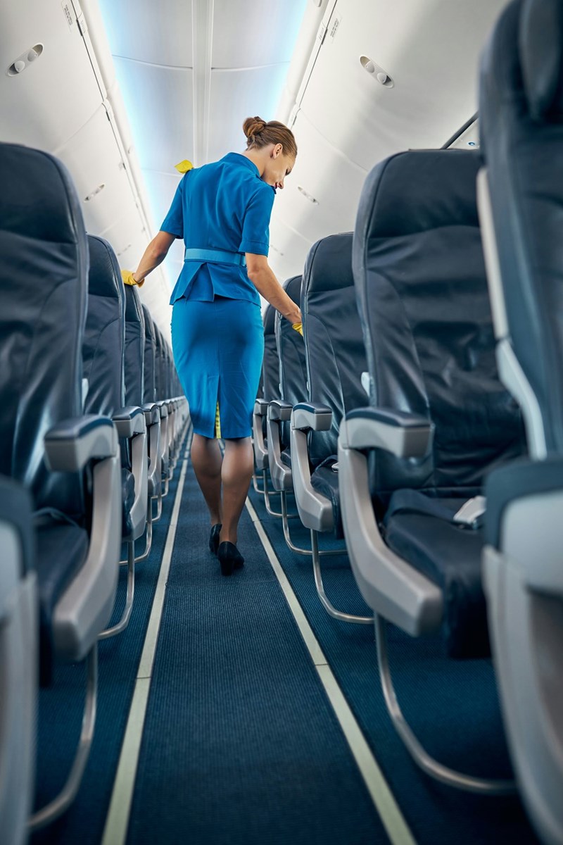 Flight attendant walks down the aisles before a flight of passengers boards.
