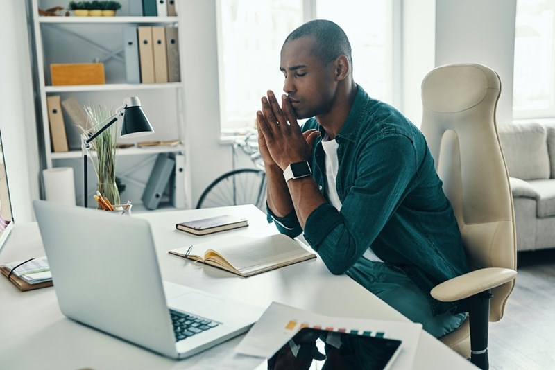 Tired young man in shirt keeping eyes closed while sitting in the office