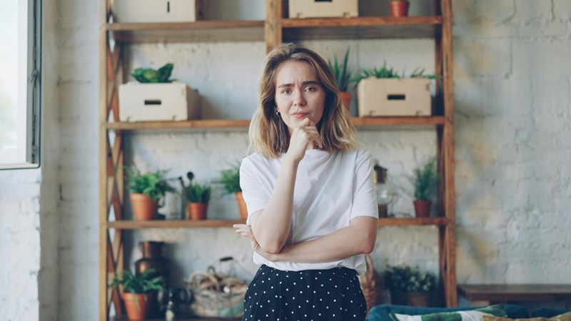A young woman with a hand on her chin looks thoughtful