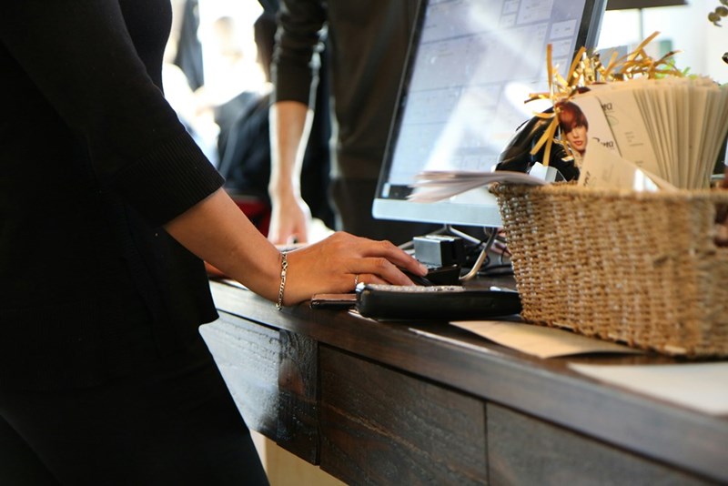 A cashier works the desk at their job