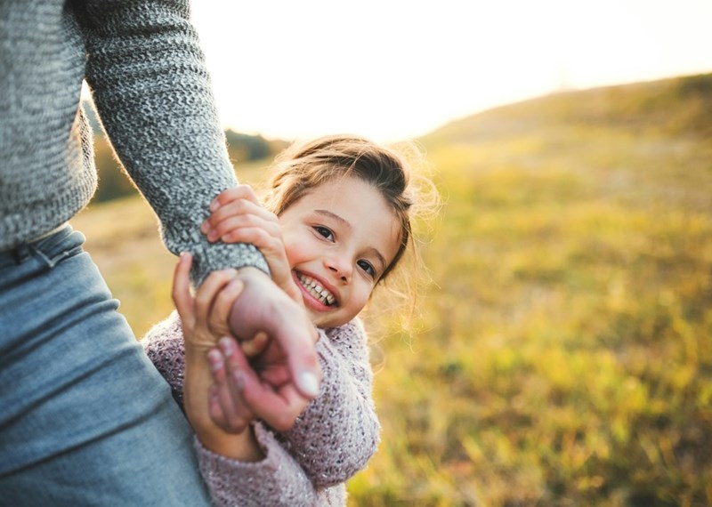 Daughter happily holds her Dad's hand while they play outside.