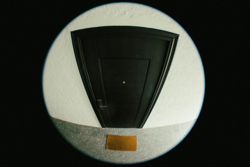 A fisheye point of view of a door and its doormat.