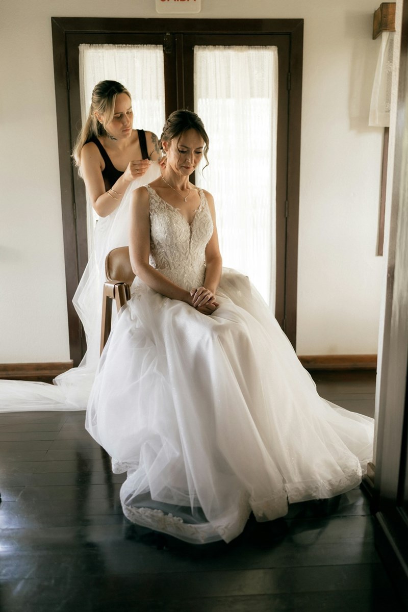 A quiet pre-wedding moment as the bride gets her finishing touches with help from a friend.