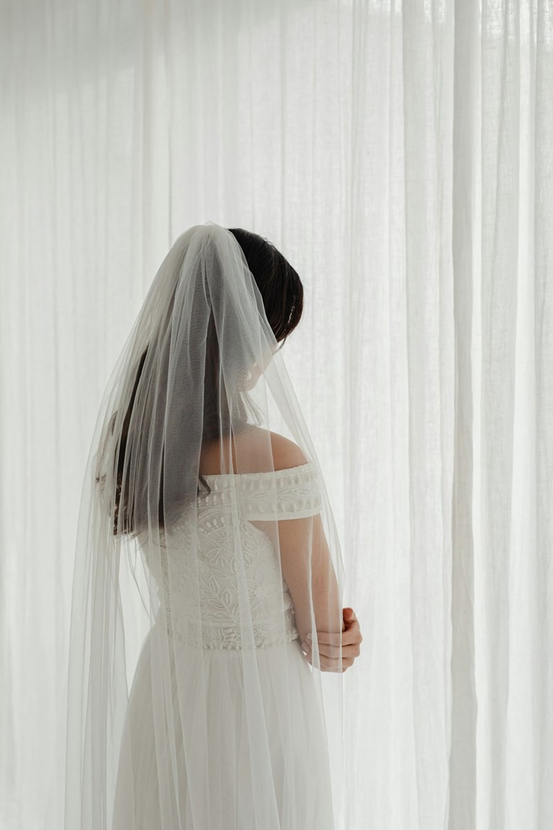 A soft, reflective moment as the bride stands alone, wrapped in light and anticipation.