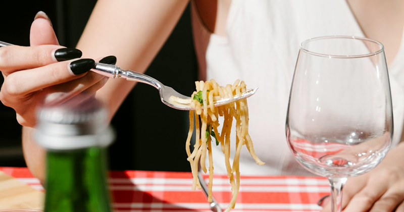 A woman's hand picks up a forkful of pasta