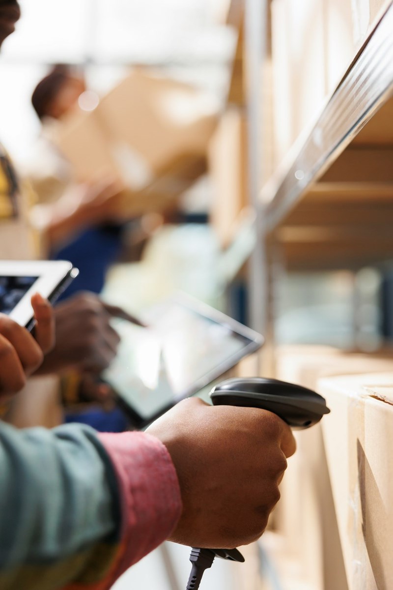 Distribution warehouse worker arm scanning a cardboard box code logistic manager checking goods