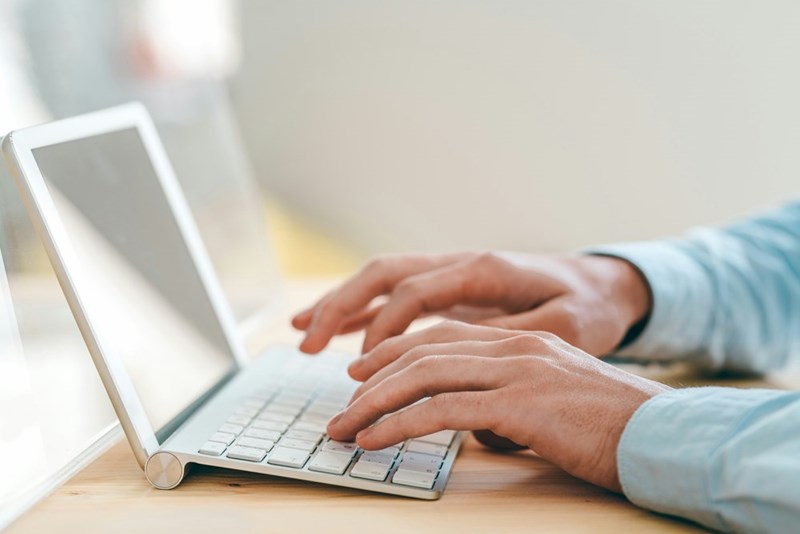 A pair of hands typing in the computer.