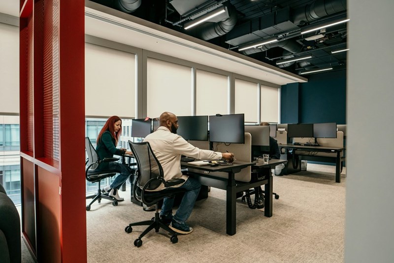 Two coworkers sit at their desks in silence in an otherwise empty office.