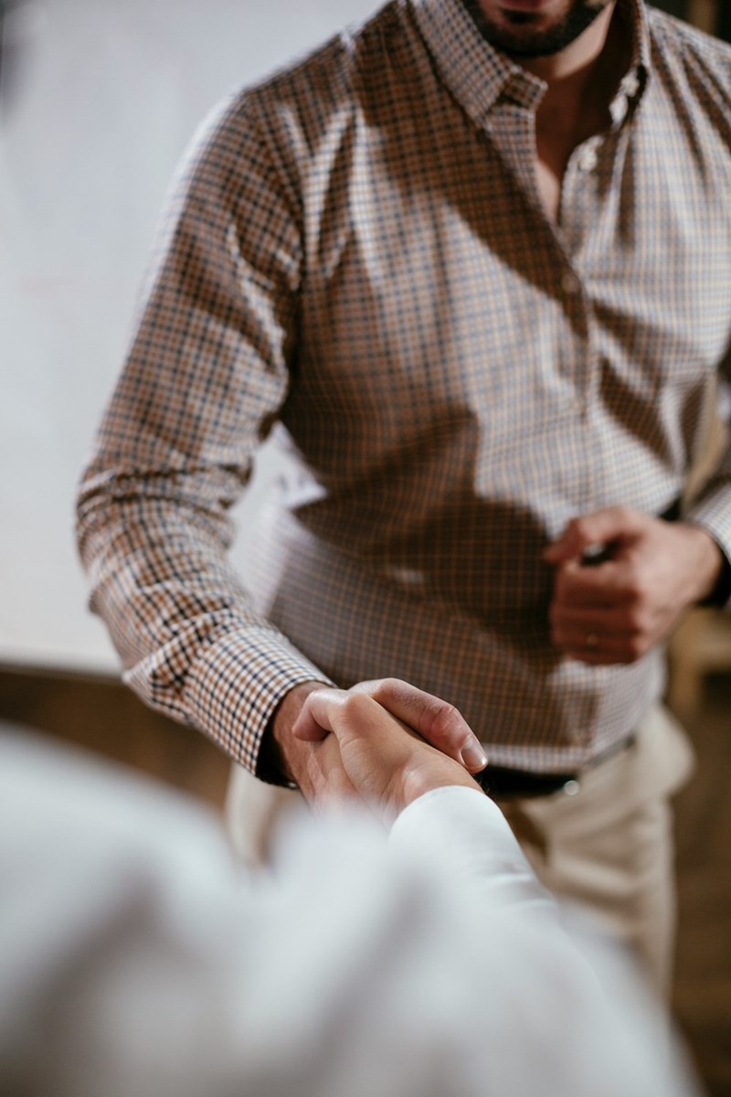 Two men dressed in business casual shaking hands, potentially making a deal