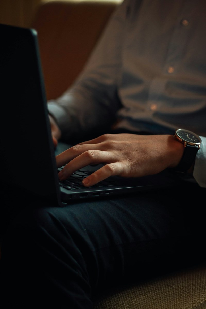 A person professionally using a laptop computer on a couch