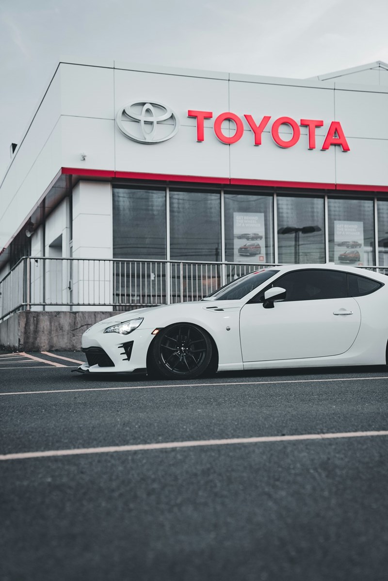 A white sport cars parked outside a Toyota car dealership.