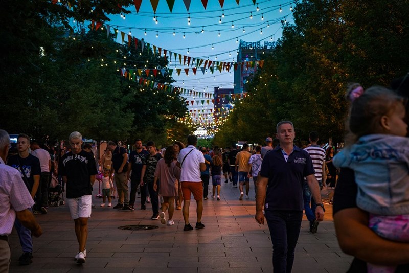 A crowd of people walking down a street at night