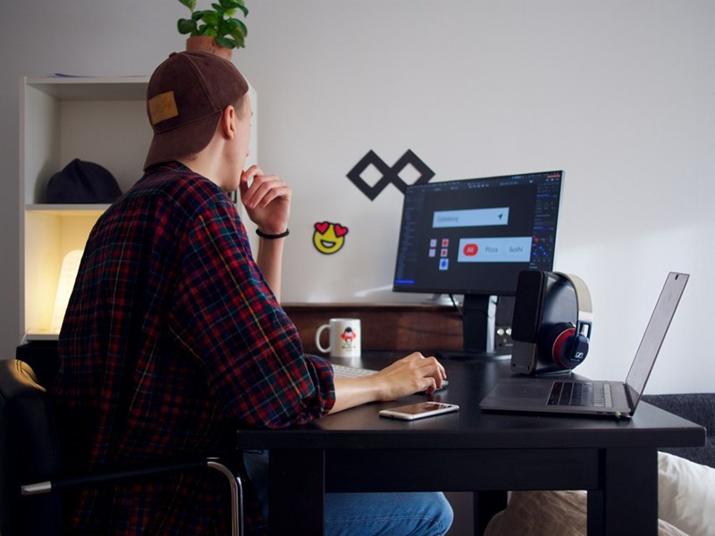 A person sits at a desk focused on their computer, deep in thought while working on a design.