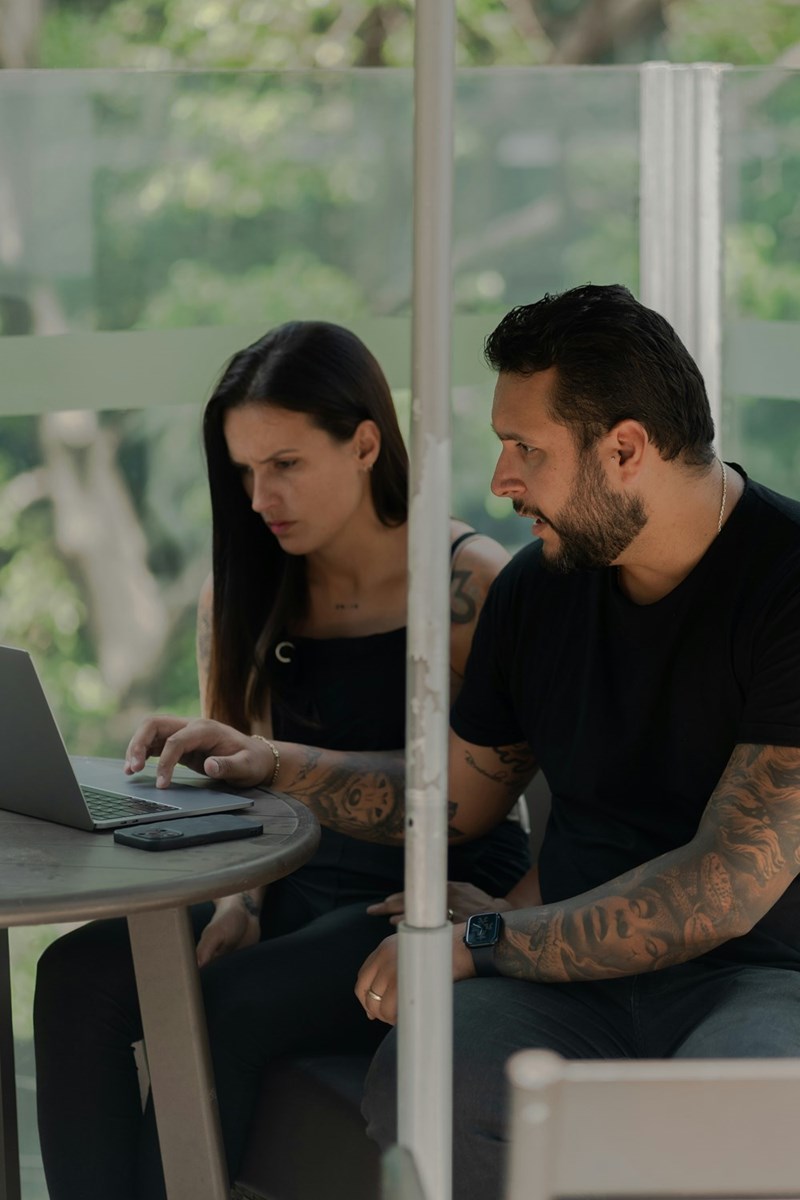 Man and woman reviewing laptop together with focused and concerned expressions.