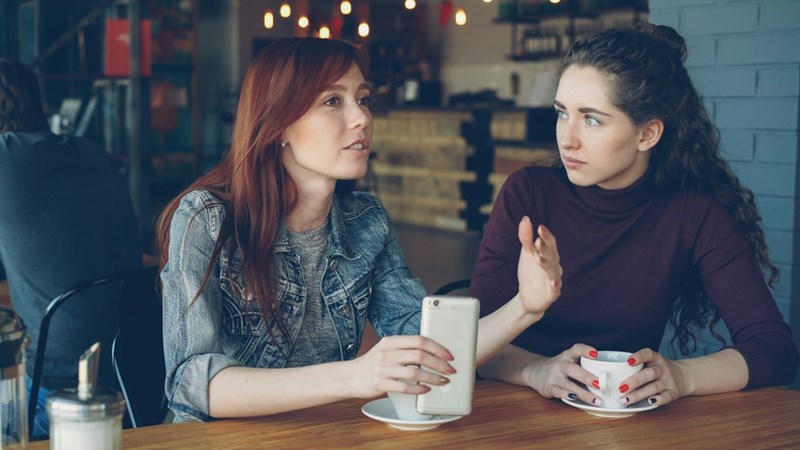 Two friends have a conversation over coffee at a cafe