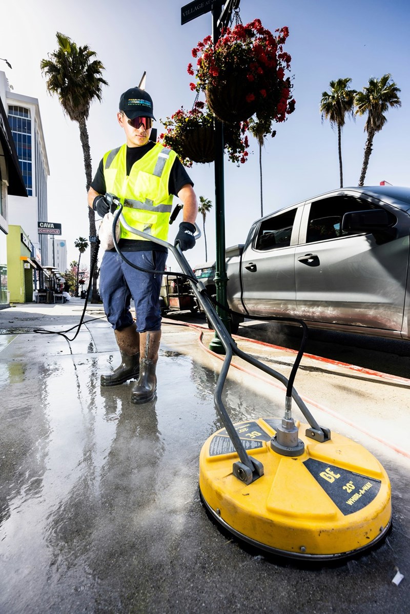 Pressure washer smiles while washing sidewalks.