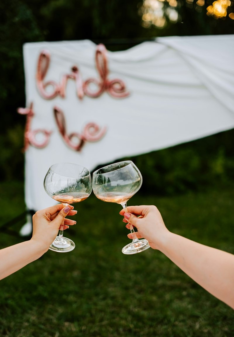 Women cheersing with pink champagne with a ‘bride to be' sign in the background