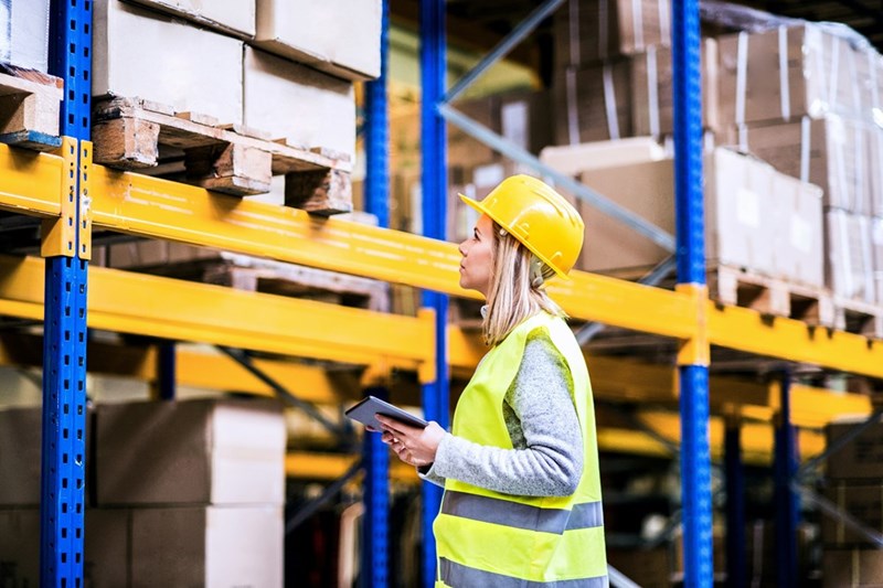 A young warehouse employee inspects a storage setup.