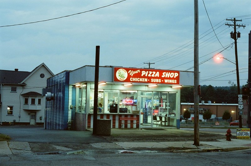 The exterior of a local Pizza Shop against a blue sky.