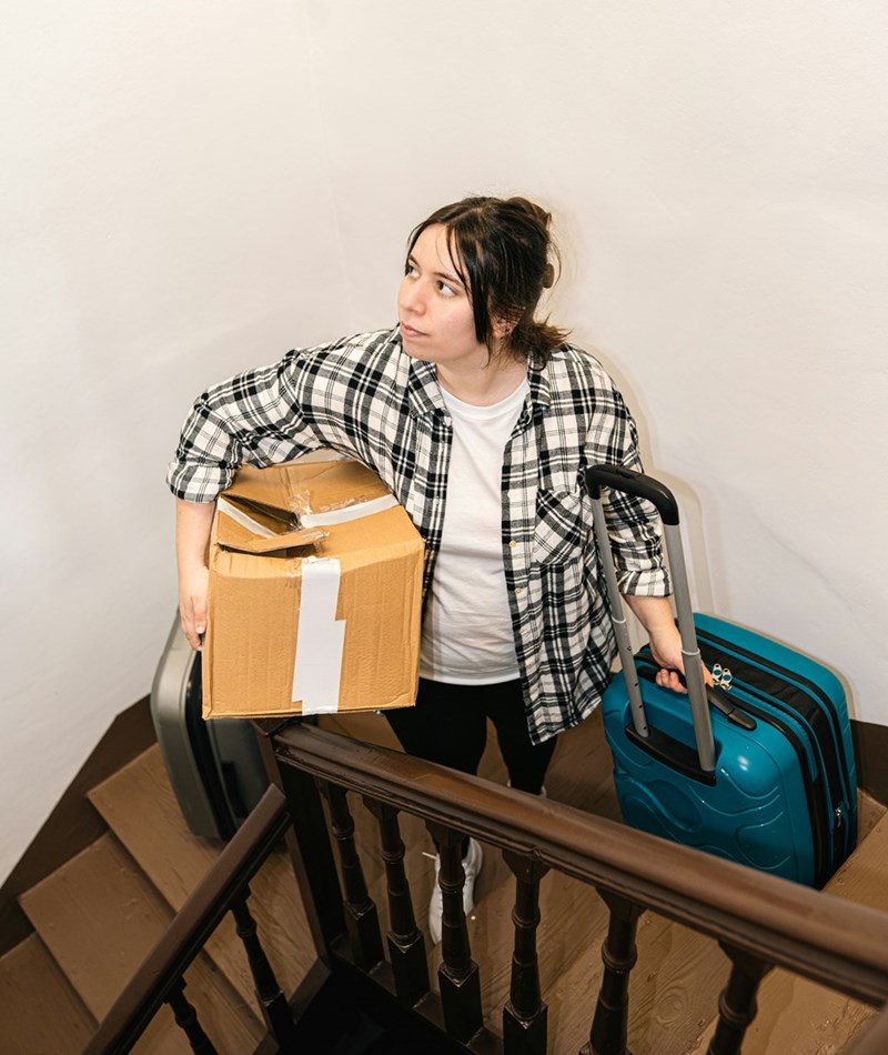 Woman carrying boxes and suitcases up the stairs