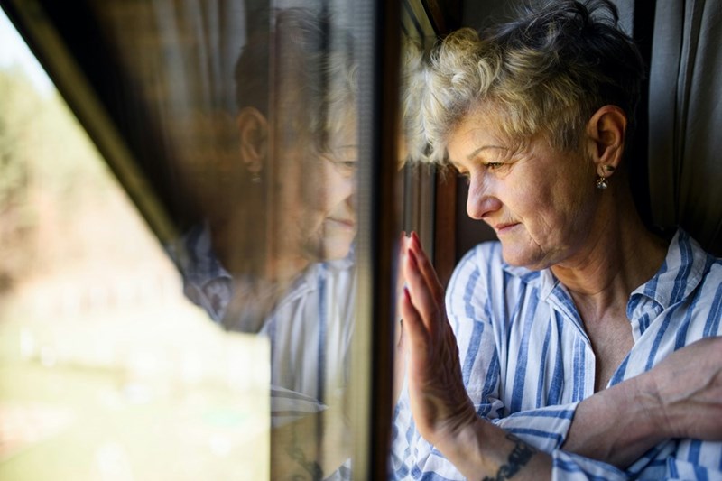 Senior woman looking out the window at home.