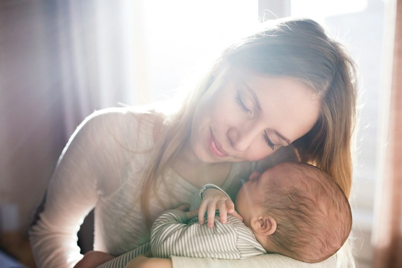 A peaceful moment as a mother gently holds her baby close, bathed in soft natural light.
