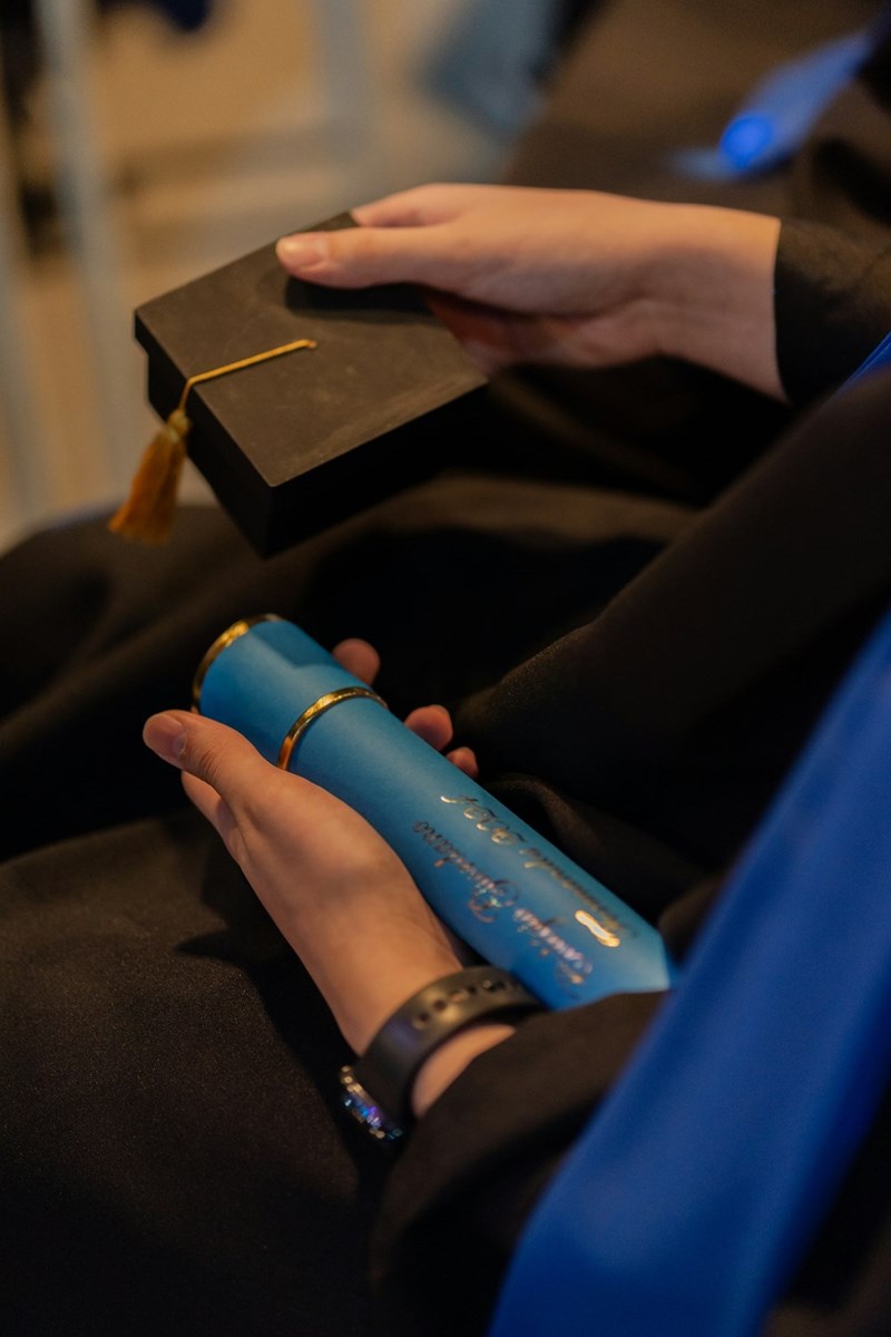 A graduate holds their cap and diploma, reflecting on the moment and what comes next.