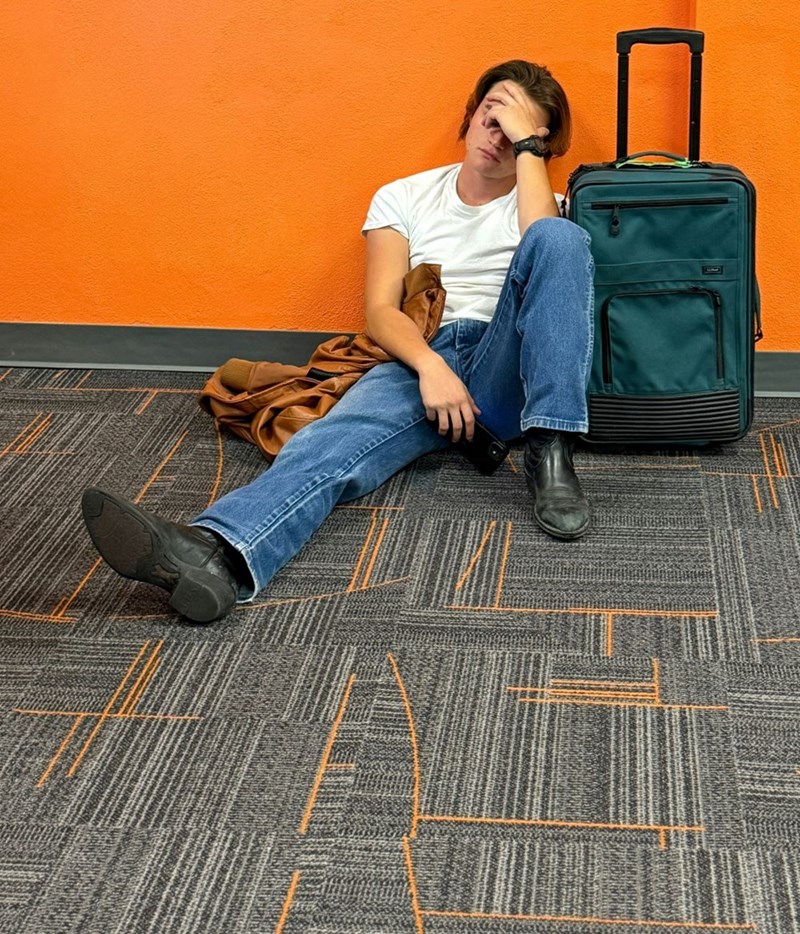 Man sitting on floor with luggage looking tired