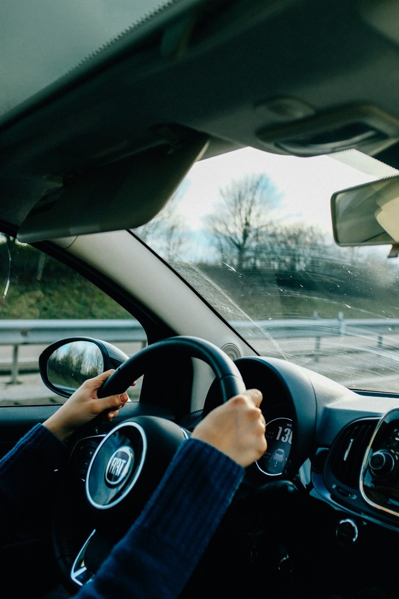Woman holding the steering wheel driving down the street