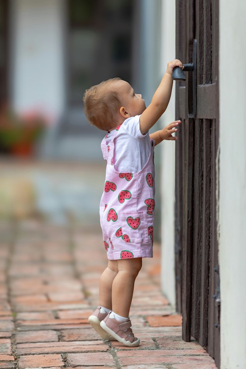 Toddler reaching for a gate latch outdoors