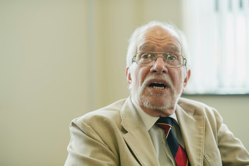 An elderly man with glasses is speaking