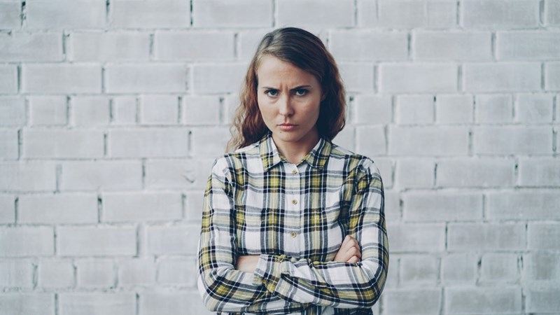 Young woman with arms crossed looks annoyed