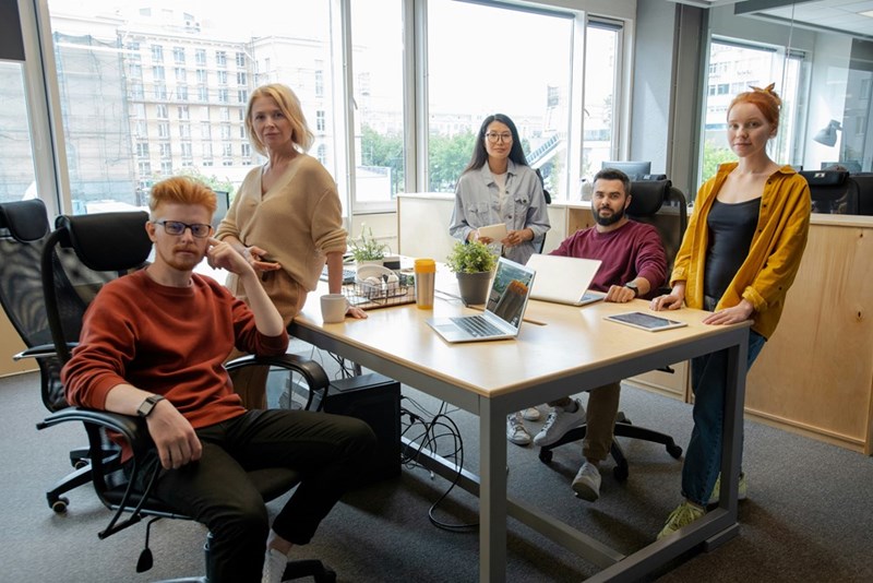 Group of business people gathered by table in office against window for brainstorming and discussion of ideas and strategies