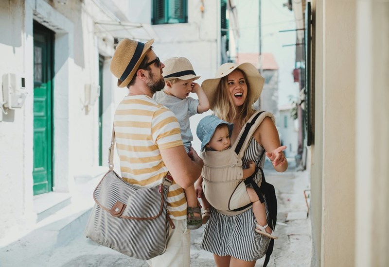 Young family with children walking in town on summer holiday