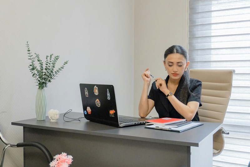 Woman works at a desk with a laptop.