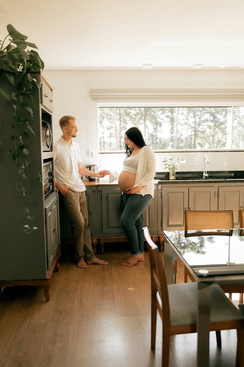 Pregnant woman and partner together in a bright modern kitchen.