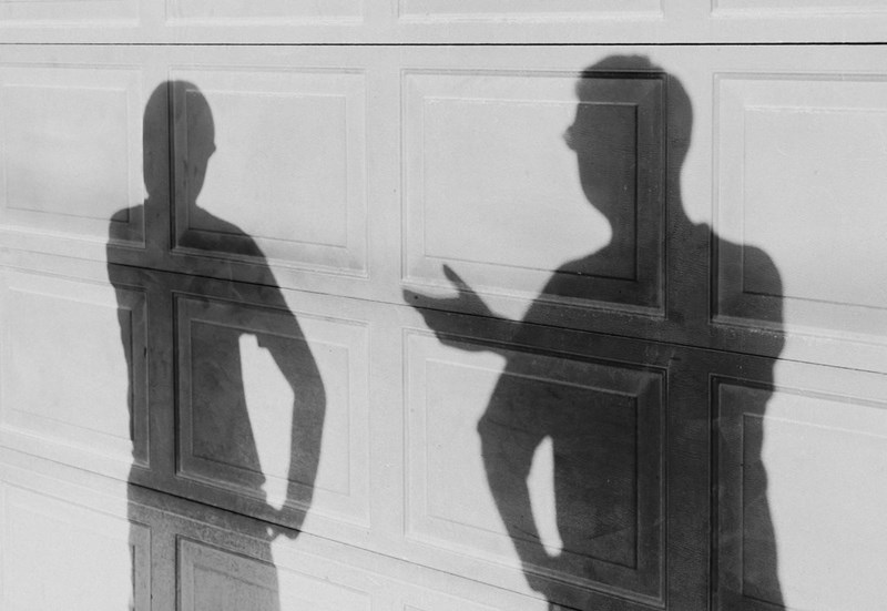 Two shadows of people talking against a garage door