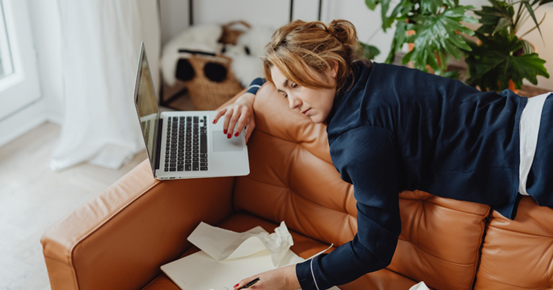 Tried woman lying on a couch while working